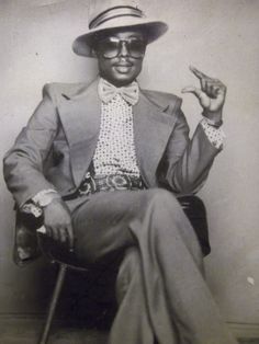 A man in the funky styles of the 70s, wear bell bottom pants, jacket and hat